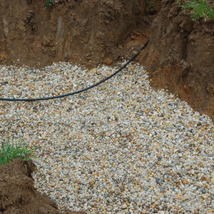 Gravel is filled into a recently excavated dry well